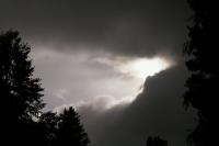 Photo of the sun peeking out from behind some dark storm clouds after a rainy day.